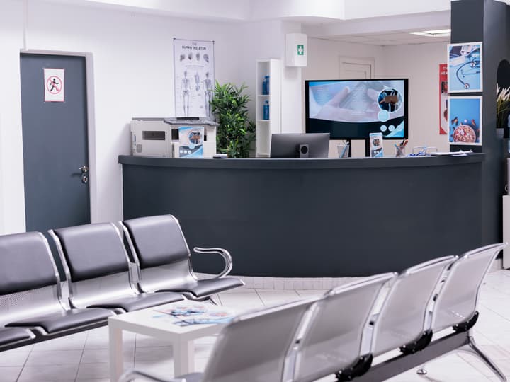 A bright, empty clinic reception desk with a waiting area