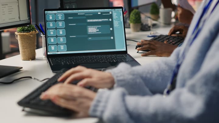 Hands typing on a laptop showing an AI chat assistant