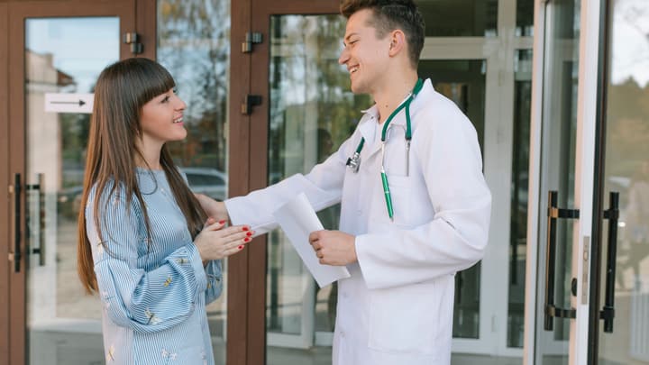 A doctor greeting a patient at a clinic entrance