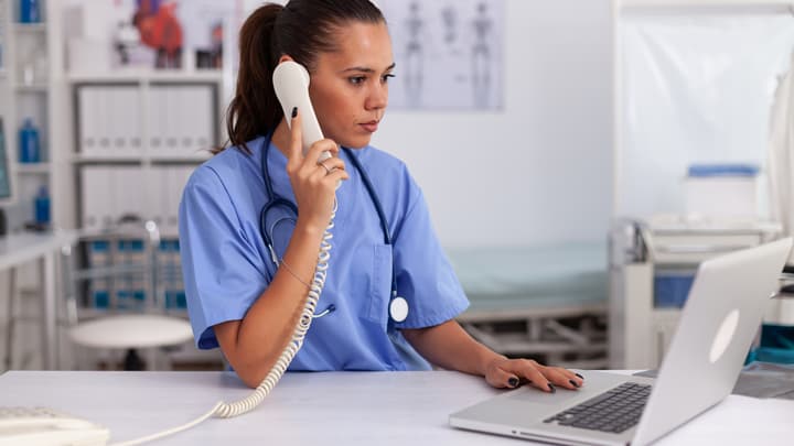 A clinic team member answering the phone at a busy desk