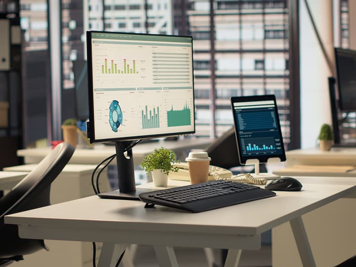 A bright, modern office desk with reports on screen