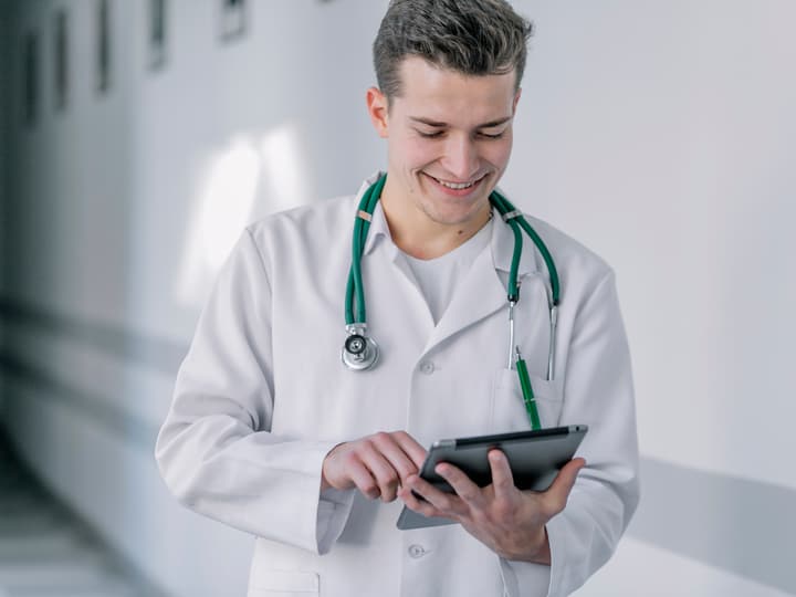 A smiling doctor reading a plan on a tablet