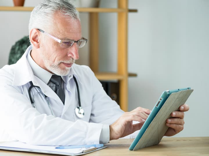 A doctor reviewing results on a tablet in his office