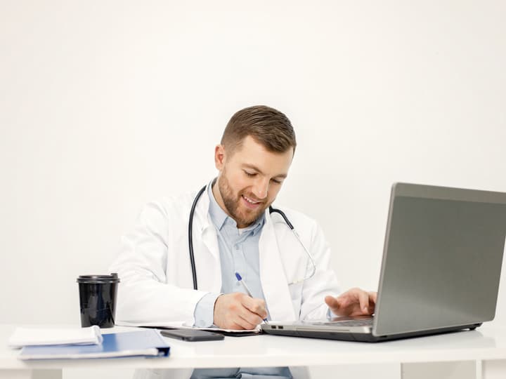 A doctor planning at his desk with a laptop