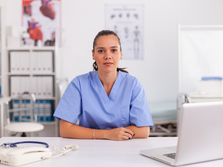 A smiling clinic team member at a front desk with a computer
