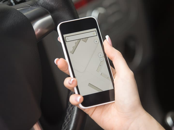 A hand holding a phone showing a map search