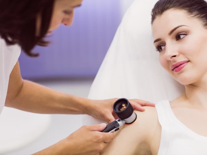 A dermatologist examining a patient’s skin with a dermatoscope