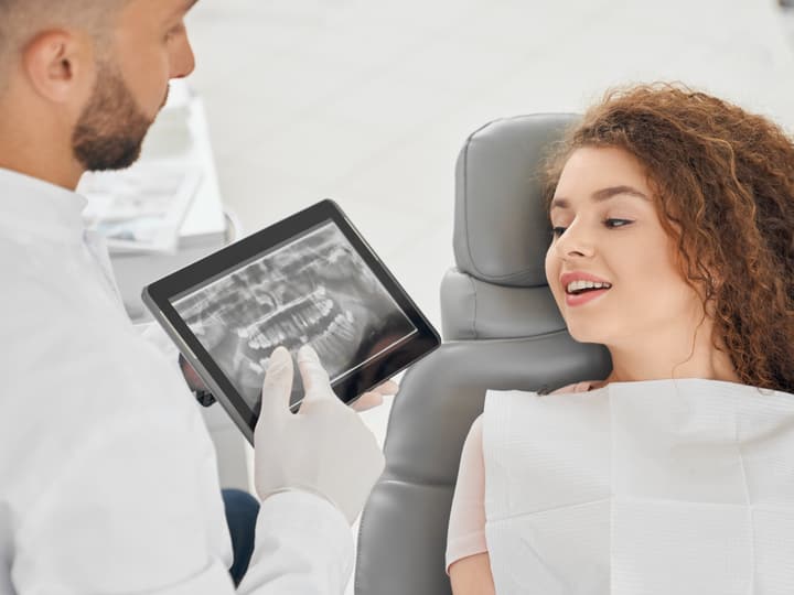 A dentist showing a patient her dental X-ray on a tablet