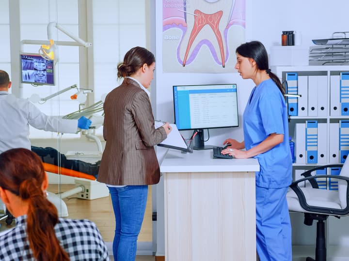 A patient checking in at a busy dental office front desk