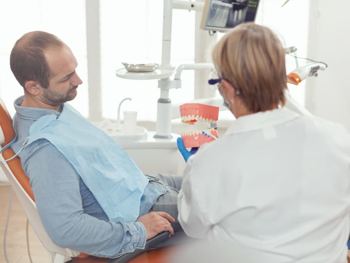 A dentist explaining a procedure to a patient with a jaw model