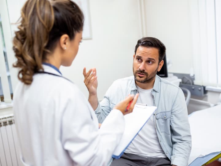 A doctor talking with an adult patient during a check-up