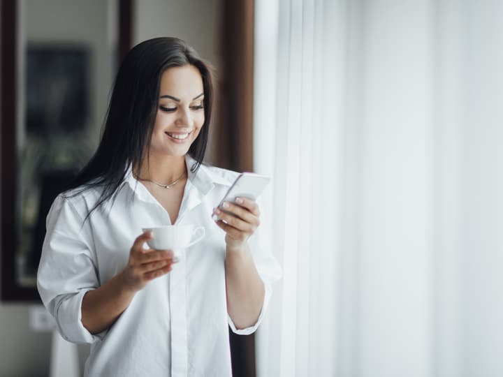 A woman with a coffee looking up a local clinic on her phone