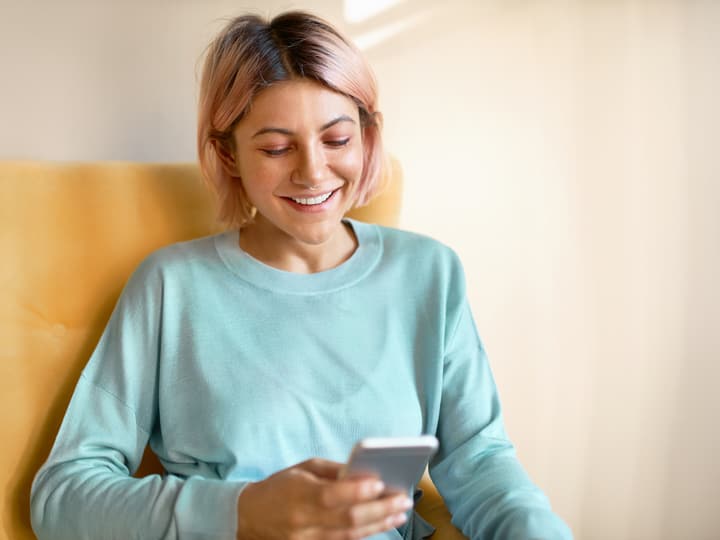 A smiling young woman reading a message on her phone