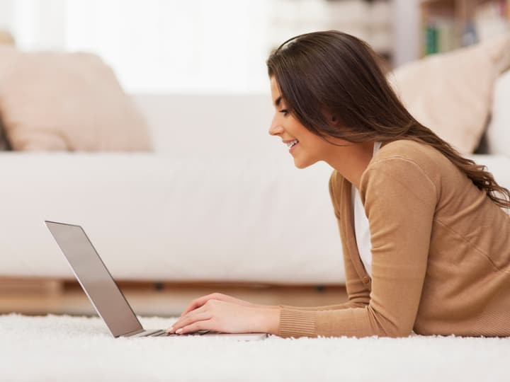 A smiling woman searching on her laptop at home